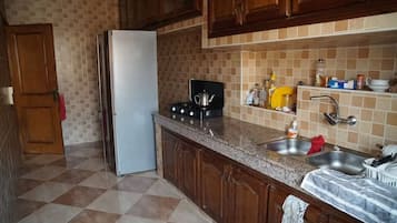 Eine Küche mit Kühlschrank, Herd, Spüle und einer gefliesten Spritzschutzwand.