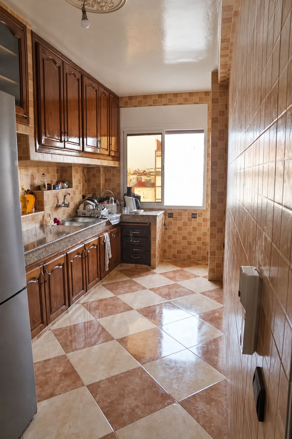Una cucina con mobili in legno, un frigorifero in acciaio inossidabile, una parete rivestita di piastrelle e una finestra vista.