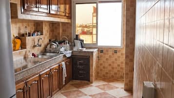 Una cocina con armarios de madera, un refrigerador de acero inoxidable, un salpicadero de azulejos y una ventana con vistas.