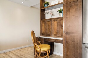 A kitchen with wooden cabinets, a built-in stove, and a chair with a yellow cushion. - Kona Reef#A1: Sand & Surf Beachfront Corner, No Stairs (Kailua Kona)