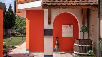 Ein Gebäude mit roter Fassade, einem Ziegeldach und einer kleinen Außenbereich-Sitzgelegenheit mit Tisch und Stühlen.