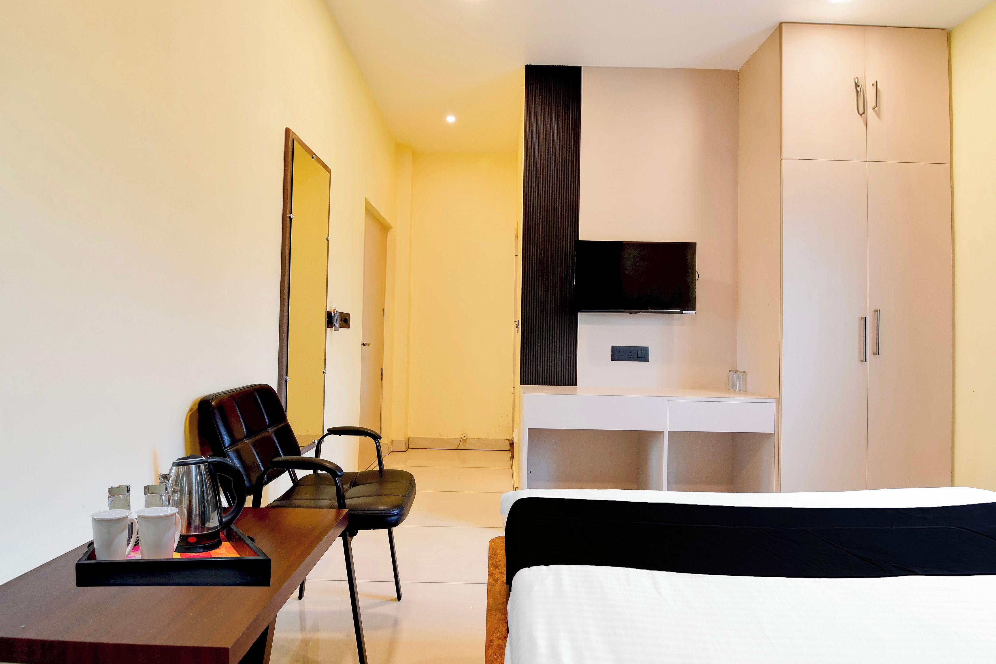 A hotel room with a bed, a desk with a chair, a television, and a wardrobe.