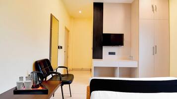 A hotel room with a bed, a desk with a chair, a television, and a wardrobe.