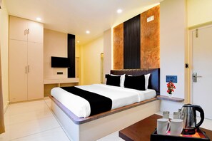 A hotel room with a bed, bedside table, TV, wardrobe, and a coffee station.