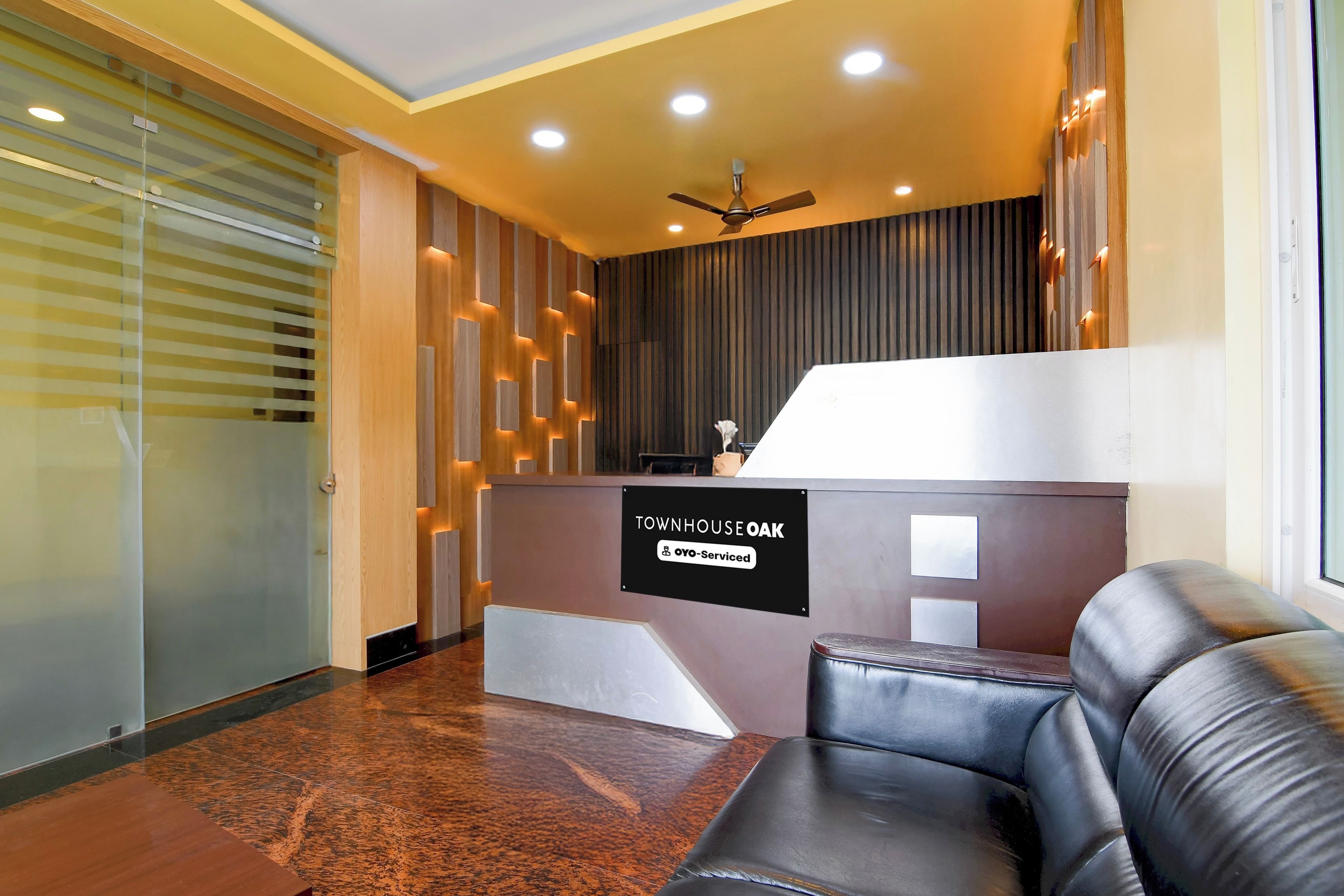 A reception area with a modern design, including a reception desk, a leather sofa, and a ceiling fan.