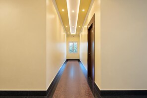 A long, narrow hallway with a dark floor, light walls, and a ceiling with recessed lighting.