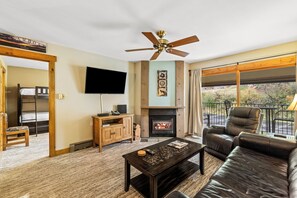 A living room with a fireplace, a television, a sofa, and a ceiling fan. - Ski, Soak & Snuggle | Ski-In/Out + Fireplace (Steamboat Springs)