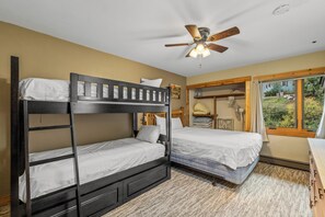 A bunk bed room with a ceiling fan, a window with curtains, and a view of the outdoors. - Ski, Soak & Snuggle | Ski-In/Out + Fireplace (Steamboat Springs)