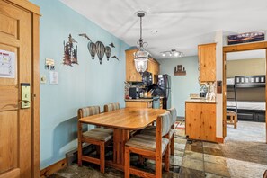 Cocina compacta con comedor, armarios de madera y microondas integrado.