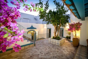 A courtyard with a tiled floor, a staircase, a tree, and potted plants.