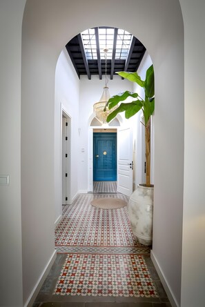 A hallway with a patterned floor, a blue door, and a plant.