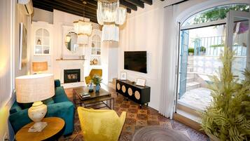 Un salon avec une cheminée, un canapé, un fauteuil, une table basse, un téléviseur et une vue sur l’extérieur.