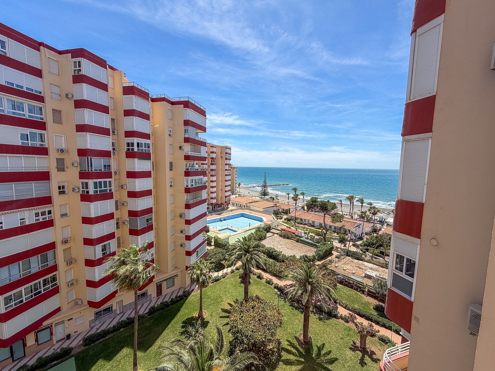 Ein Hochhotel mit Pool, Palmen und Blick auf den Ozean.