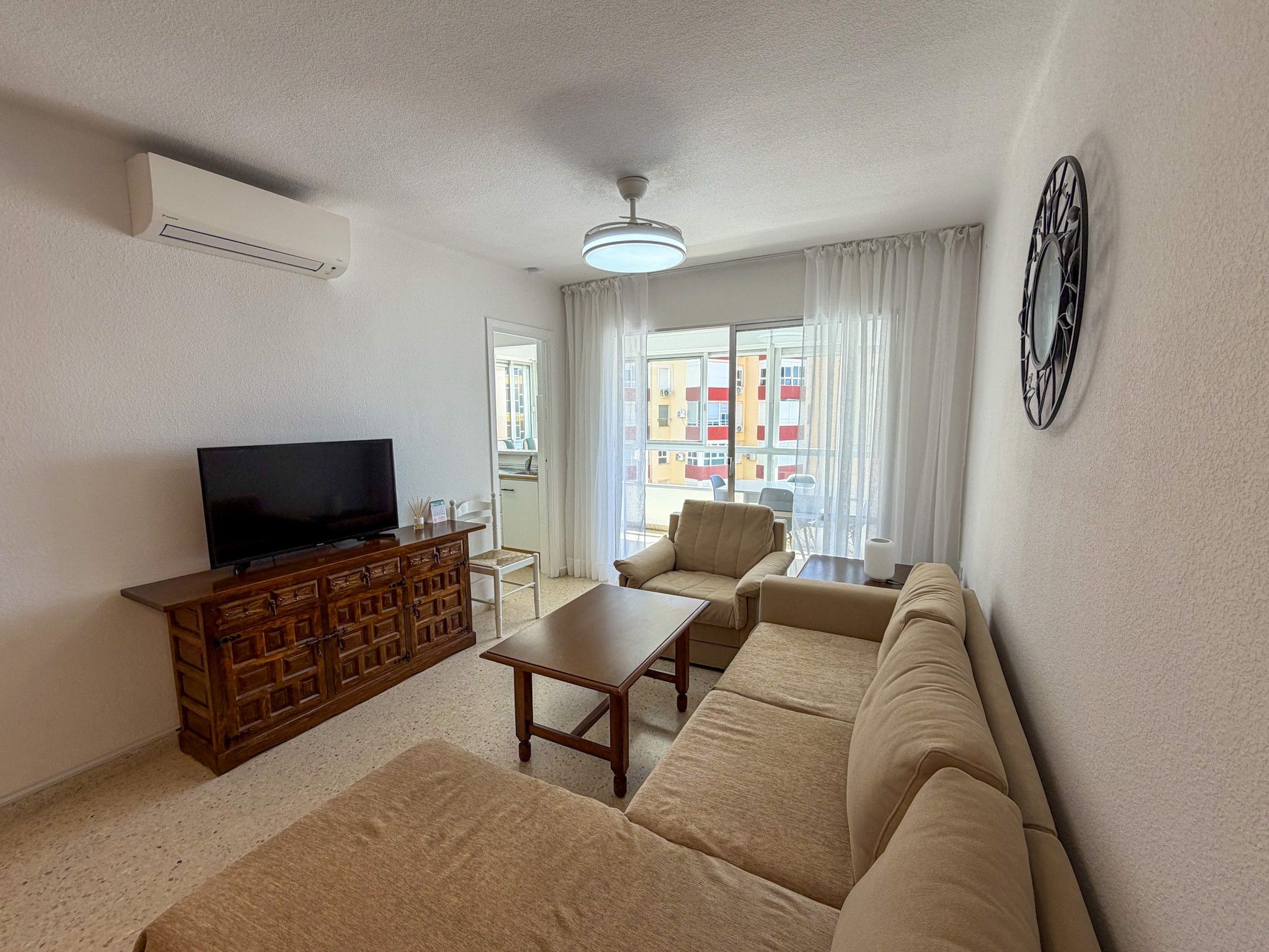 A living room with a television, sofa, coffee table, and a decorative wall piece.