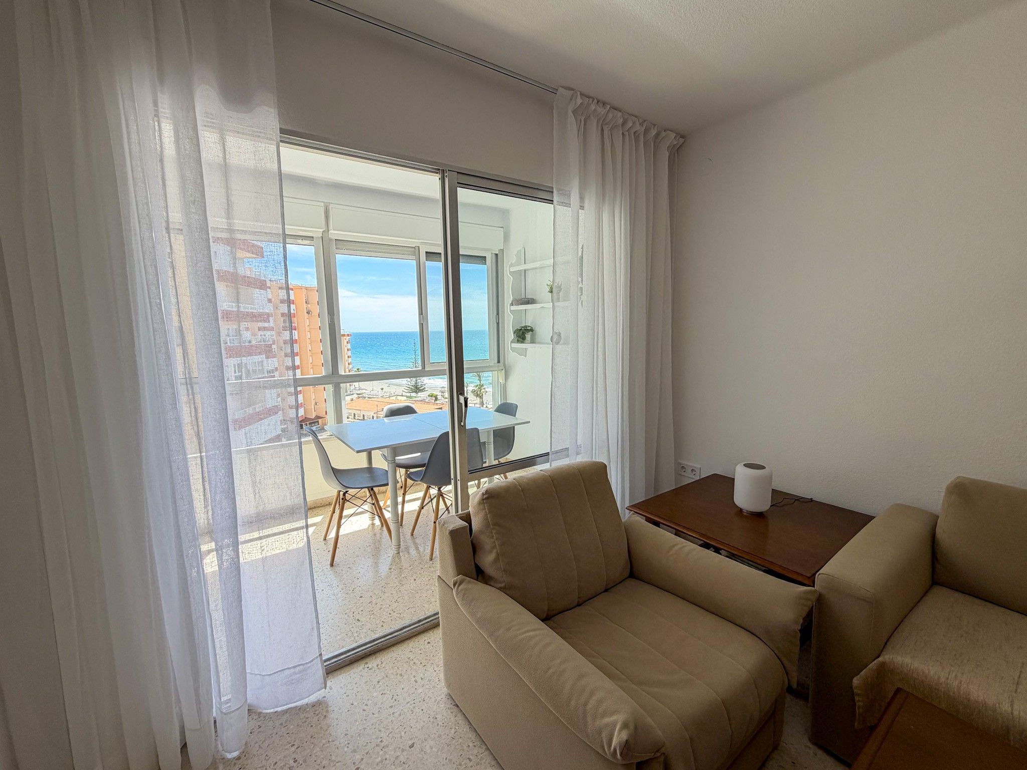Een hotelkamer met een balkon, een tafel en twee stoelen.