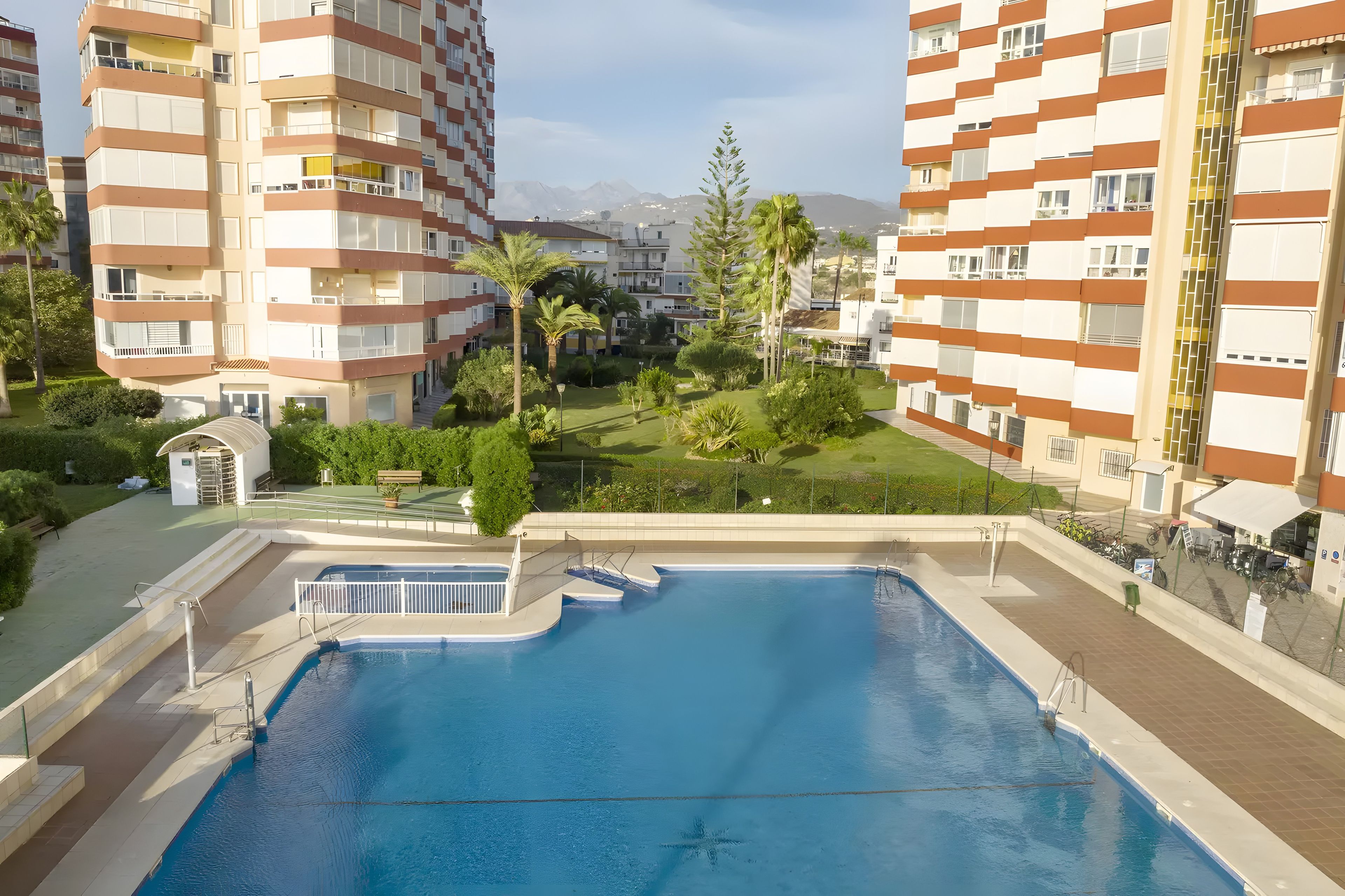 Un edificio residencial con piscina, balcones y vistas a montañas.