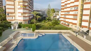 Un edificio residencial con piscina, balcones y vistas a montañas.