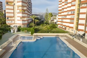 Un edificio residencial con piscina, balcones y vistas a montañas.