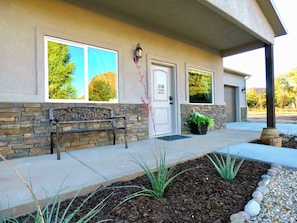 A building with a stone facade, a bench, a door with a no pets sign, and a landscaped area with plants. - Downtown Kanab Hideaway | Walk to Shops & Dining (Kanab)