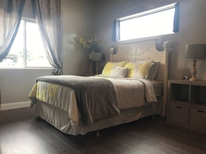 A bedroom with a bed, bedside tables, a lamp, and a window with curtains. - Downtown Kanab Hideaway | Walk to Shops & Dining (Kanab)