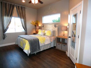 A bedroom with a bed, nightstands, a window with curtains, a door, and a ceiling fan. - Downtown Kanab Hideaway | Walk to Shops & Dining (Kanab)