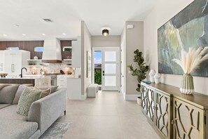 A modern kitchen with white cabinets, a built-in oven, and a dining area with a grey sofa. - Luxury Home - Close to Beach -Saltwater Pool & Spa (Naples)