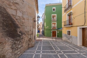 Un carrer estret amb edificis a ambdues bandes, un paviment de rajoles i un cel serè.