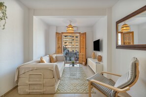 Habitació d'hotel amb un llit, un sofà, una cadira, una televisió i vista a l'exterior.