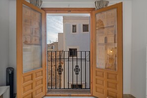 Una porta de fusta oberta que dona a un balcó amb una reixa de metall.
