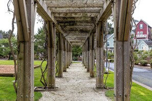 Ein überdachter Gang mit Holzsäulen und einem Kiesweg.