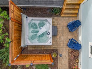 Un jacuzzi con terraza de madera, dos sillas Adirondack azules y una planta en maceta.