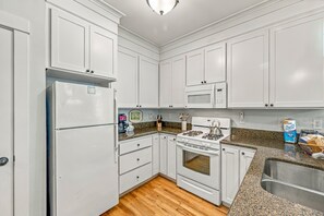 A kitchen with white cabinets, a refrigerator, a microwave, a stove, and a granite countertop. - Olivia Beach Beauty; Hot Tub, Grill, Near Beach Access (Lincoln City)