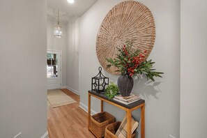 A hallway with a wooden floor, a woven wall hanging, a vase with red berries, a black lantern, and a woven basket. - Pinebrook Haven - Lake Arrowhead - Waleska, GA (Waleska)