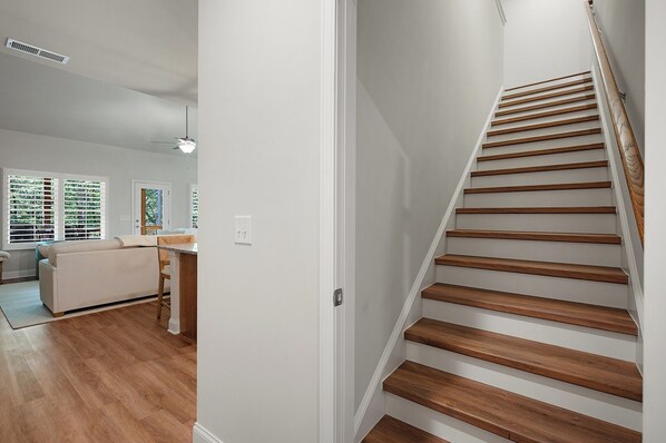 A modern interior with a wooden staircase, a kitchen area, and a living space with a sofa and dining table.