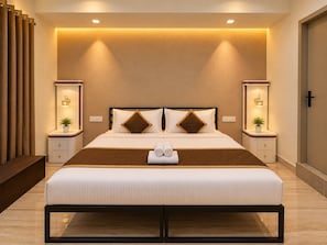 A modern hotel room with a large bed, bedside tables, and a bench.