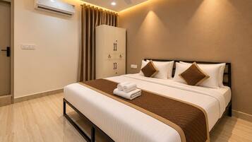 Habitación de hotel con cama, armario, aire acondicionado, ventilador de techo y puerta de baño.