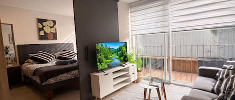 A modern living room with a bed, sofa, TV, and a balcony with a view.