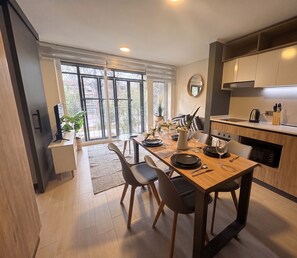 A modern kitchen with a dining area, large windows, and a view of the outdoors. - Edificio Quinta Vista by Domus Travels (Quinta Normal)