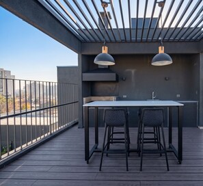 An outdoor dining area with a table and chairs, a metal railing, and a view of the cityscape. - Edificio Quinta Vista by Domus Travels (Quinta Normal)