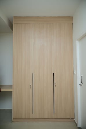 A large, light-colored wardrobe with two doors and a shelf. - Hotel Giove (Bangalore)