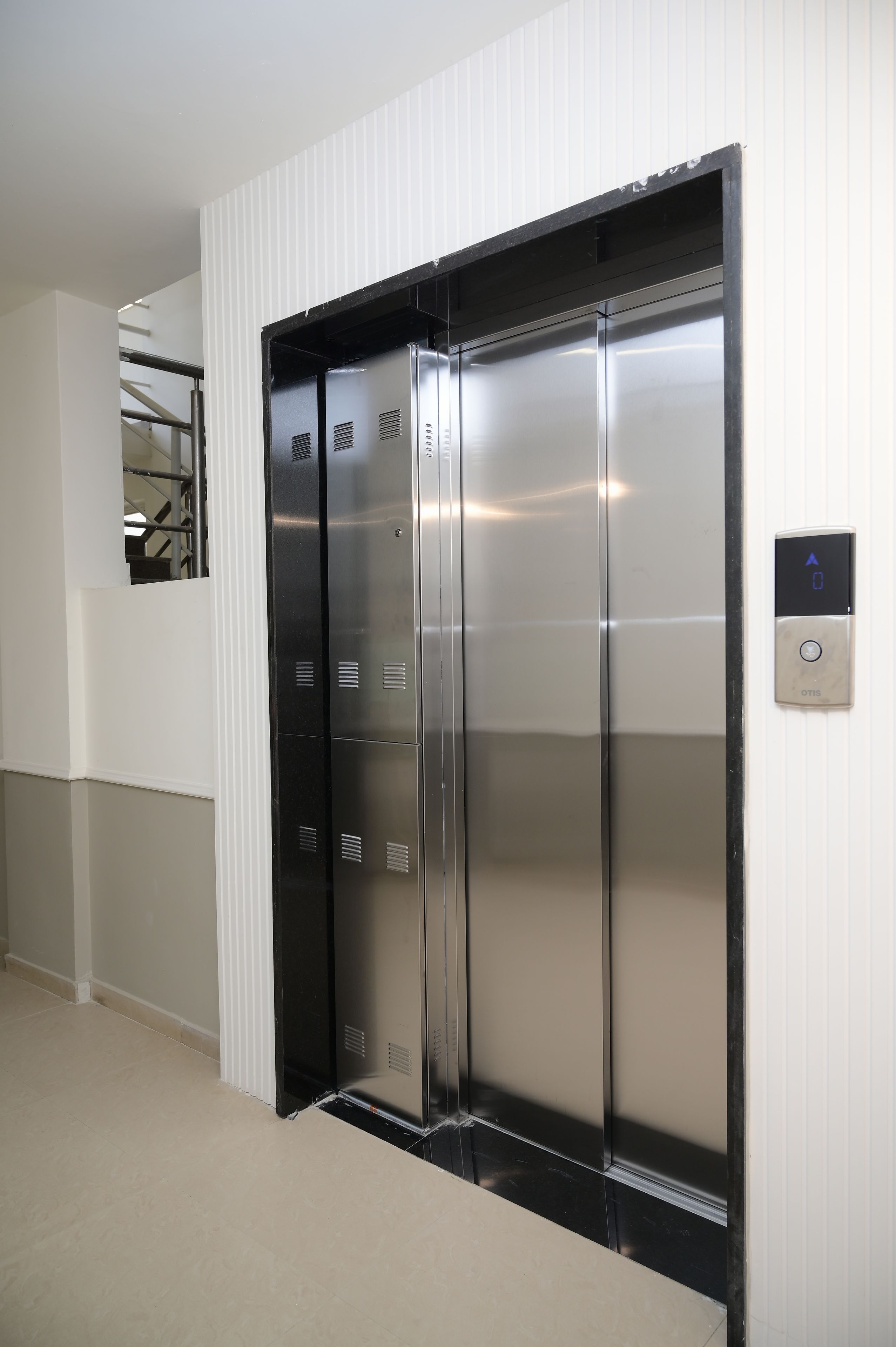 A modern elevator with a metallic finish, a control panel with directional arrows, and a small display.