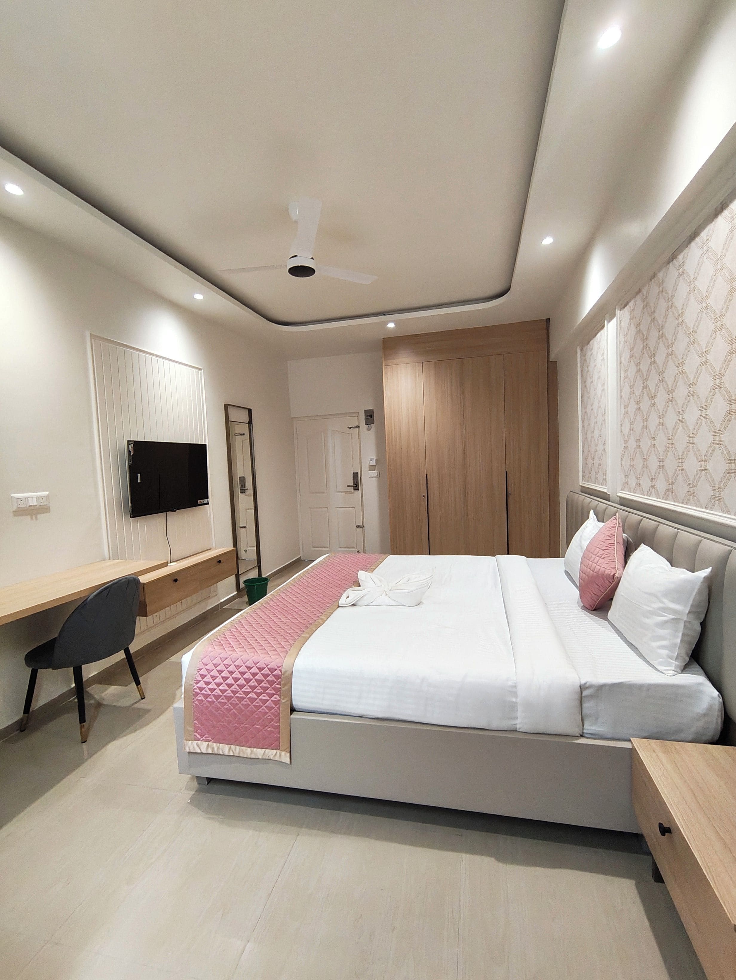 Une chambre moderne comprenant un lit, une table de chevet, un bureau, une chaise et un téléviseur.