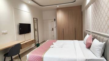 Une chambre moderne comprenant un lit, une table de chevet, un bureau, une chaise et un téléviseur.