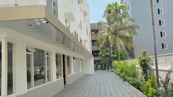 A building with a covered walkway, large windows, and a tiled ground.