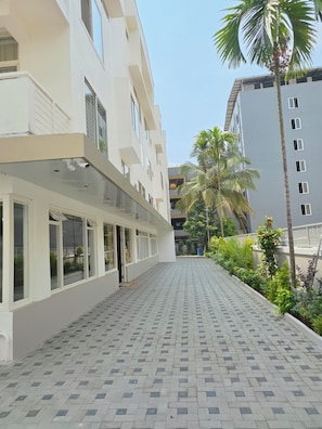 A building with a covered walkway, large windows, and a tiled ground. - Hotel Giove (Bangalore)