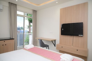 A hotel room with a bed, a desk, a chair, a TV, and a window with curtains. - Hotel Giove (Bangalore)