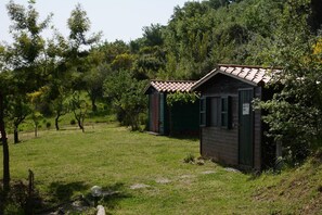 Eine kleine Holzhütte mit einem Ziegeldach, umgeben von Gras und Bäumen.