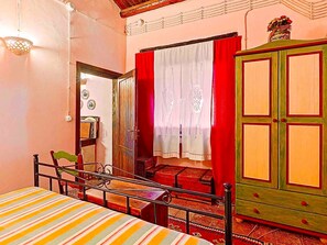 A room with a bed, a chair, a wardrobe, and a door leading to another room. - Country house 'Casa Vinzeria' with private pool, private terrace and Wi-Fi (Castelbuono)