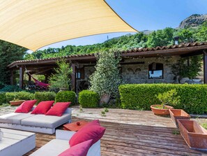 A wooden deck with outdoor seating, a pergola, and a stone building with a tiled roof. - Country house 'Casa Vinzeria' with private pool, private terrace and Wi-Fi (Castelbuono)