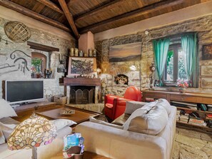A rustic living room with a fireplace, leather sofa, and stone walls. - Country house 'Casa Vinzeria' with private pool, private terrace and Wi-Fi (Castelbuono)